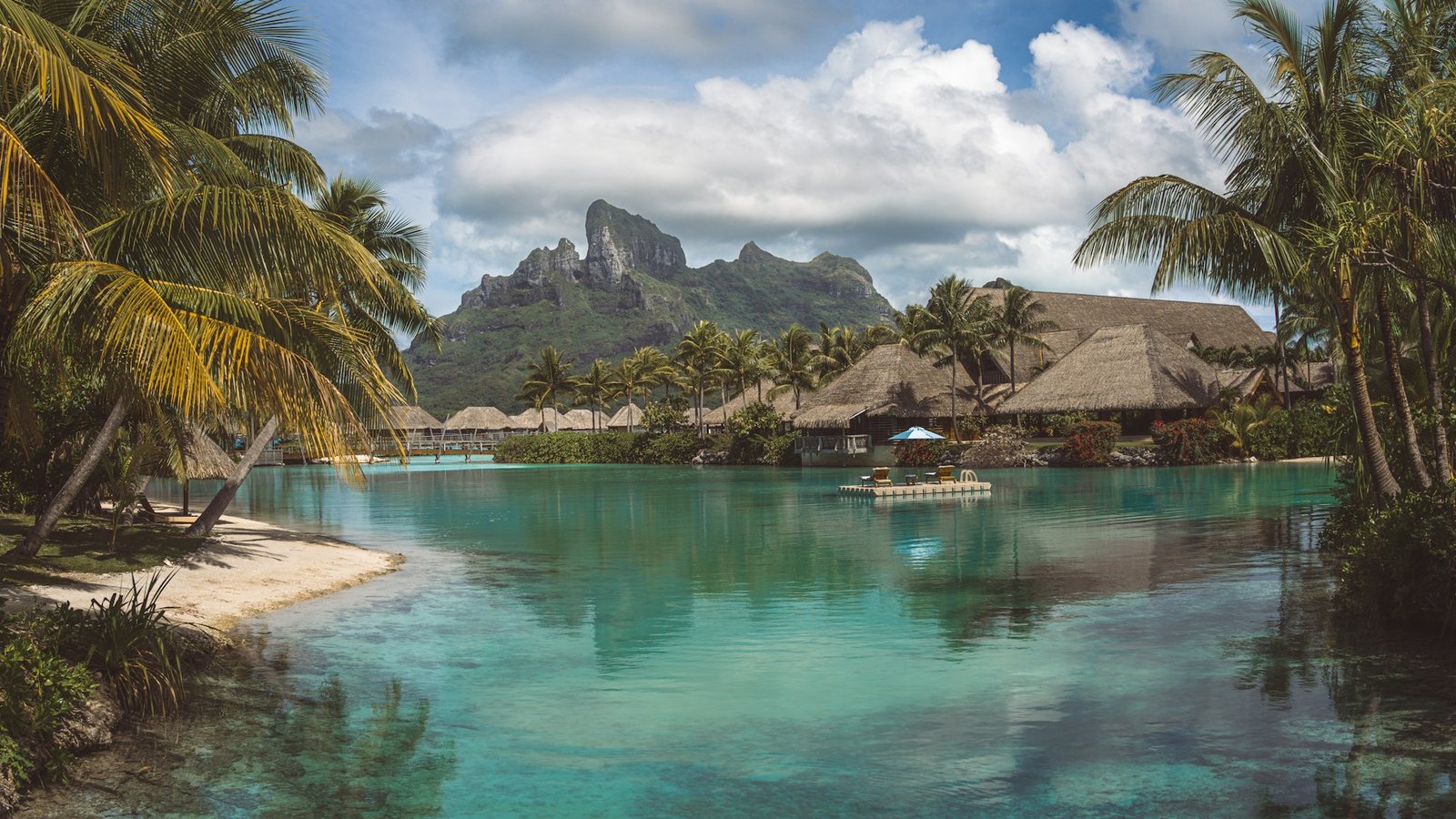 A small boat crossing a palm-fringed Bora Bora lagoon