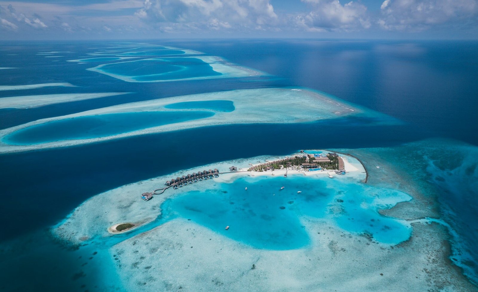 A tropical Maldives resort and coral reef seen from above