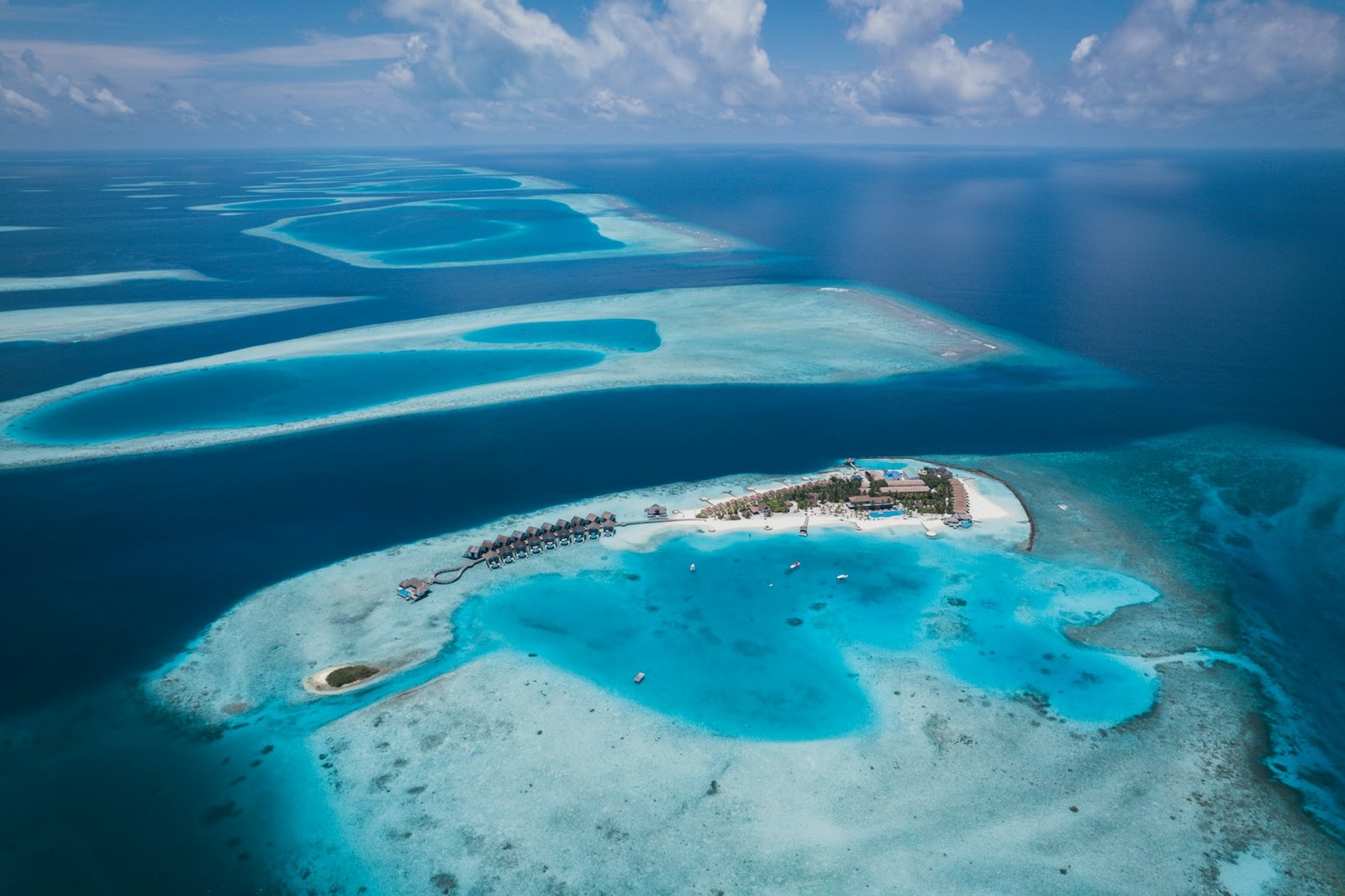 A tropical Maldives resort and coral reef seen from above